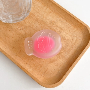 Close-up of pink translucent fish-shaped silicone phone grip on a wooden tray