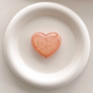 Detail of pink heart-shaped resin grip with shimmering gold and colorful sequins