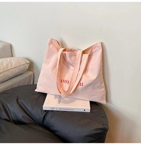 Detail view of the pink canvas tote bag showing the Anyu Cai lettering and texture