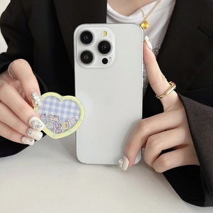 Detail of heart-shaped checkered phone grip with cute charms on white matte case
