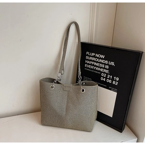 Makrodetail der gewebten Textur und des silbernen Metallrings an der cremefarbenen Tasche