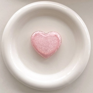 Detailed macro of pink glitter heart phone socket grip with sparkling sequins on a white tray
