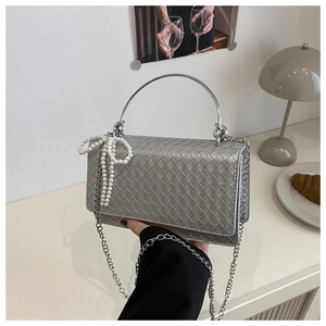 Detail of silver woven leather bag with round metal handle and pearl bow charm