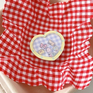 Close-up of heart-shaped phone grip with cute cartoon dog and rabbit icons on a checkered base