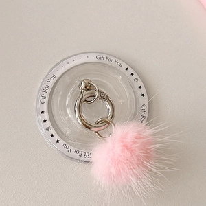 Detail of pink faux fur pompom phone grip with silver ring on gift card packaging