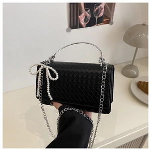 Detail of black woven shoulder bag with silver handle, chain and pearl bow charm