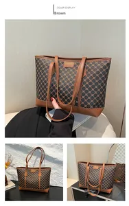 Detail der braunen Tragetasche mit Retro-Monogramm-Muster und metallener Logoplatte