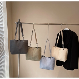 Details minimalistischer Tragetaschen in vier Farben mit schmalen Ketten-Schulterriemen