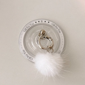 Close-up of white plush fur pendant with silver metal lobster clasp and ring detail