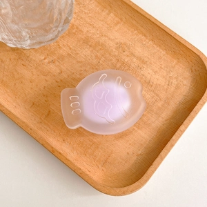 Close-up of translucent purple matte fish phone stand on a light wooden tray