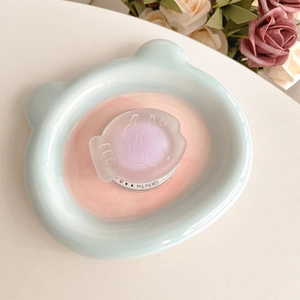 Close-up of frosted fish-shaped phone grip with Gift For You print on ceramic tray