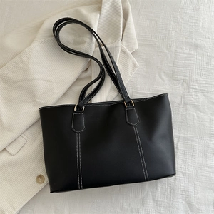 Minimalist black tote bag with white contrast stitching and gold hardware for daily commute