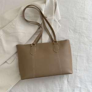 Minimalist khaki leather tote bag with contrast stitching and golden hardware rings
