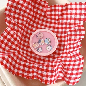 Detail of round pink phone grip featuring cute cartoon animals on a red checkered cloth