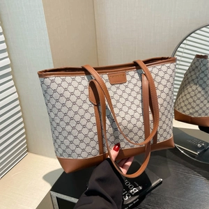 Grand sac cabas en toile monogramme grise avec anses en cuir marron devant un miroir