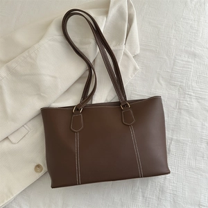 Minimalist brown leather tote bag with white contrast stitching and long shoulder straps