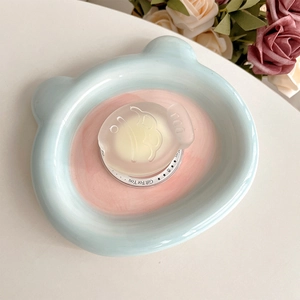 Close-up of cute bear-shaped ceramic plate with fish-shaped soap and floral background