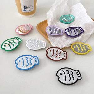 Set of fish-shaped mirror phone sockets in various colors on a white wooden tray