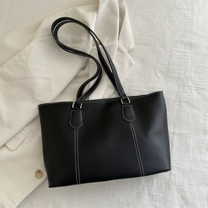Minimalist black tote bag with white contrast stitching and gold hardware finish