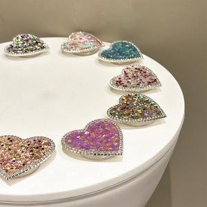 Close-up of heart-shaped glitter phone grips with rhinestone edges in various colors