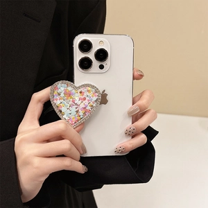 Sparkling heart-shaped phone grip with glitter and rhinestones on a white smartphone