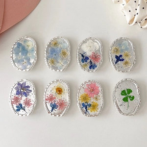 Macro view of floral oval phone stand featuring silver foil and real pressed flowers
