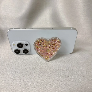 Sparkling heart-shaped phone grip with pink glitter and rhinestones on a smartphone