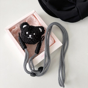 Detail of a braided black and white crossbody lanyard with a plush cartoon bear charm