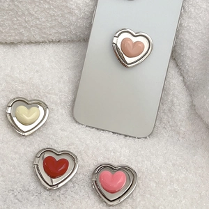 Detail showing colorful heart phone ring holders on a plush background with a silver frame