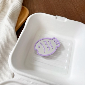Close-up of purple fish-shaped mirror phone grip placed in a white paper box