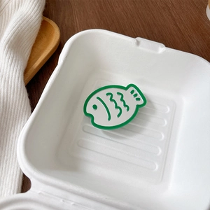 Detail of green fish-shaped retractable phone socket mirror inside a white box