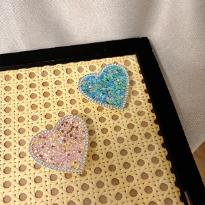 Close-up of sparkling heart-shaped phone grips with sequins and rhinestones on woven tray