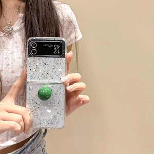 Detail of glitter case for Samsung Z Flip6 with green ball grip and clear handle strap