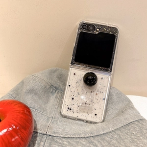 Detail of glitter Z Flip case with black sphere ring stand next to a red apple