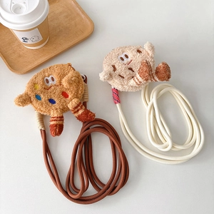 Detail of plush biscuit-shaped crossbody bags with woven cotton straps on white surface