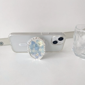 Detail of silver foil floral oval phone grip attached to a white phone with MagSafe