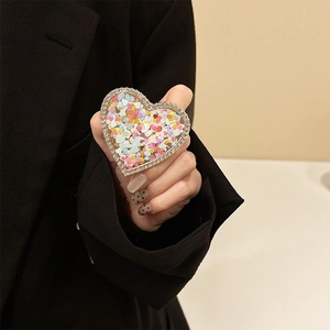 Close-up of heart-shaped phone grip with colorful sequins and sparkling rhinestones