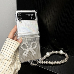 Detail of glitter flip phone case with large rhinestone bow and pearl charm bracelet