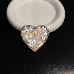 Close-up of heart-shaped glitter phone grip with rhinestones on black leather background