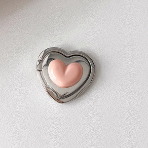 Close-up of heart-shaped folding phone stand with pink 3D heart and silver metal frame
