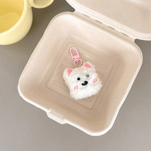 Detail of white plush puppy keychain with pink metal clasp in a stylish gift box