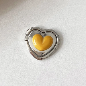 Macro shot of silver metal heart phone ring holder with a glossy yellow resin inlay