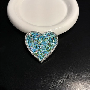 Close-up of heart-shaped phone grip with glitter sequins and rhinestone border