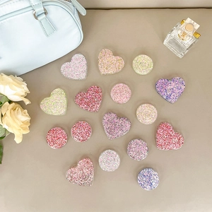 Glitter heart and round phone sockets on a stylish tabletop with fashion accessories