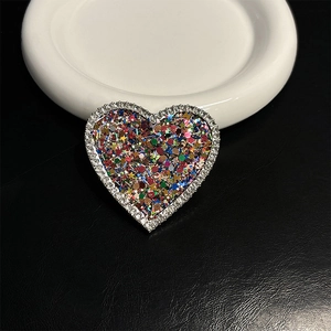 Macro shot of heart-shaped phone grip with colorful star sequins and rhinestone edges