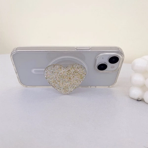 Macro detail of heart-shaped glitter phone socket with gold sequins on clear case