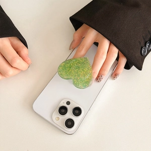 Detail of green glitter heart phone socket grip with sparkling sequins on white phone