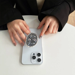 Detail der silbernen ovalen Handyhalterung mit Schmetterling und Strass auf Smartphone