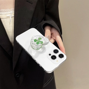 Macro detail of heart-shaped resin phone grip with a real four-leaf clover inside