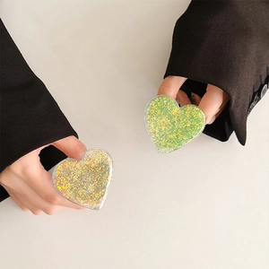 Close-up of heart-shaped glitter phone grips with colorful sequins in handheld display